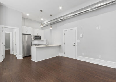 Interior living space with hardwood floors and view of newly renovated kitchen at Dickinson Lofts luxury lofts for rent in Grays Ferry