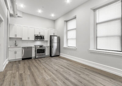 Newly renovated kitchen and living space with two windows for natural light and hardwood floors at Dickinson Lofts luxury lofts for rent in Grays Ferry